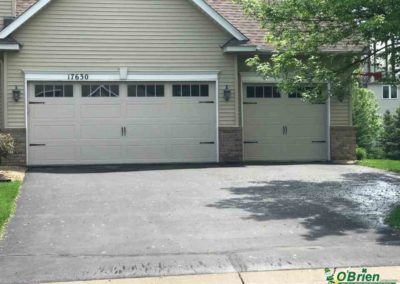 White carriage-style garage door on gray house.