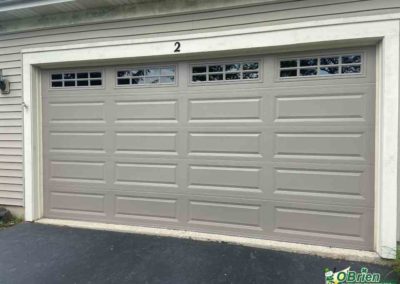 Gray panel style garage door on gray house.