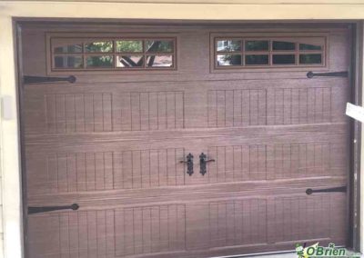 Dark oak carriage-style garage door on cream-colored house.