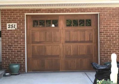 Small cedar garage door with windows on brick house.